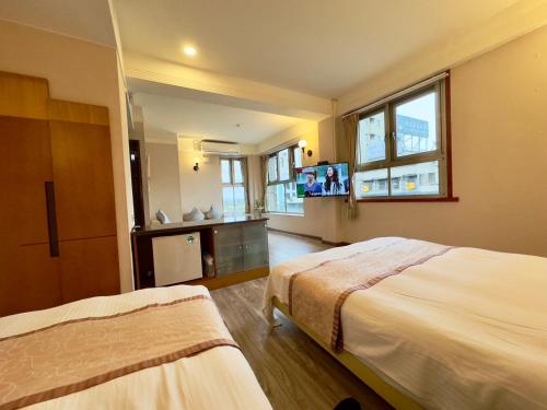 a hotel room with two beds and a flat screen tv at Tian Long Hotel in Jiaoxi