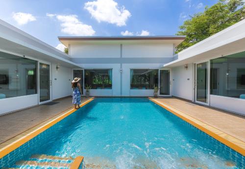 a woman standing in front of a house with a swimming pool at Bor Saen Pool Villa in Bor Saen