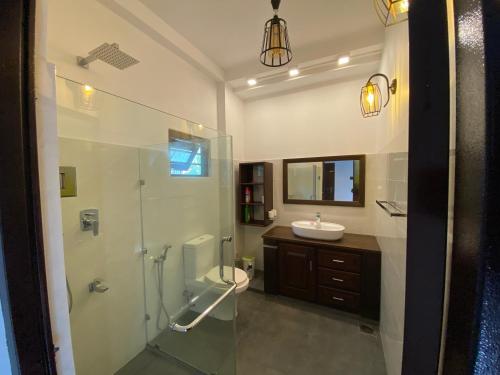 a bathroom with a glass shower and a sink at Ran Villa in Galle