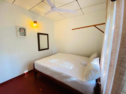 a small bedroom with a white bed and a ceiling at Ran Villa in Galle