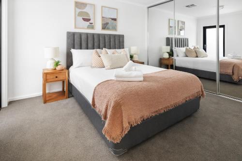a bedroom with two beds and a mirror at Clare St Apartments by Urban Rest in Port Adelaide
