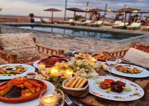 einen Tisch mit Teller mit Speisen neben einem Pool in der Unterkunft The magic of camping in Marrakesch