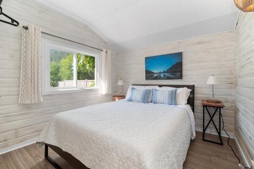 a white bedroom with a bed and a window at Lake Time Harrison in Harrison Hot Springs