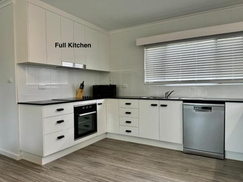 cocina grande con armarios y electrodomésticos blancos en Townsville Apartment on Paxton - First Floor, en Townsville