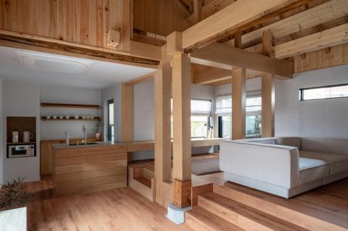 a room with a couch and a kitchen with wooden ceilings at Han Yul Jae - Hanok in Chuncheon