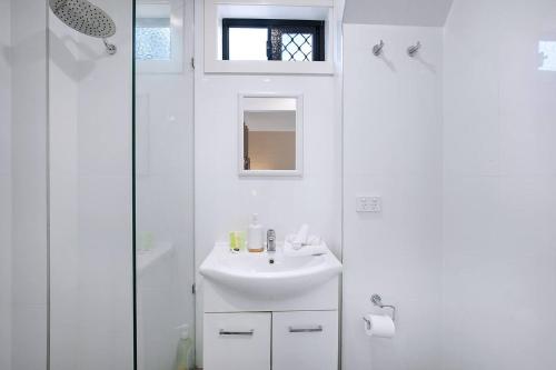 a white bathroom with a sink and a shower at The Sunny Studio - A Peaceful Riverside Abode in Brisbane