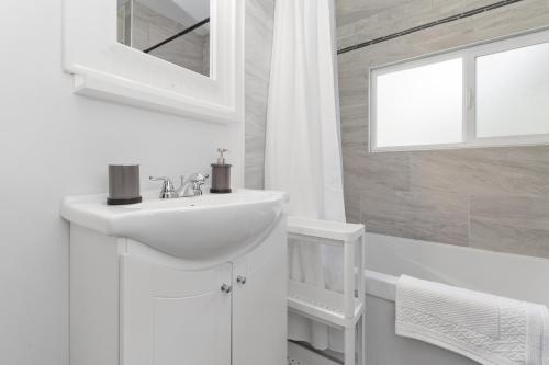 uma casa de banho branca com um lavatório e um espelho em Lake Time Harrison em Harrison Hot Springs