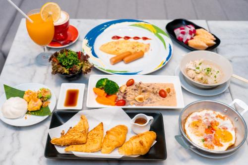 a table topped with plates of food and drinks at Amanta Hotel & Residence Ratchada in Bangkok