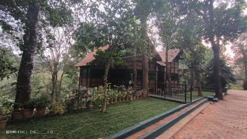 a house with a fence and some plants and trees at Tree House Wayanad in Muthanga