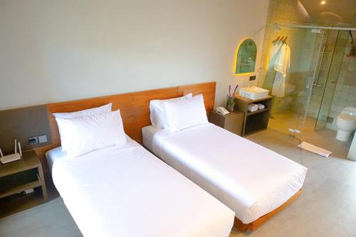 2 camas en una habitación con ducha acristalada en Agua Hotel, en Kubupenlokan