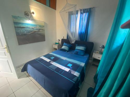 1 dormitorio con cama azul y cortinas azules en Bungalows Mathilde-non fumeur, en Bouillante