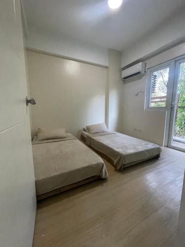two beds in a room with a window at Pocket Home in Manila