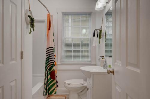 Baño blanco con aseo y lavamanos en Peaceful Park Circle Getaway, en Charleston