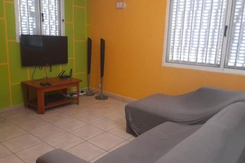 a living room with a flat screen tv and a table at Casa de Amor in Luanda