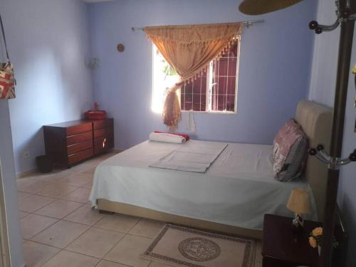 a bedroom with a bed and a window at Casa de Amor in Luanda