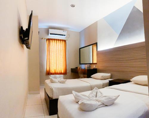 a hotel room with three beds and a flat screen tv at OS Hotel Batu Aji Batam in Batam Center
