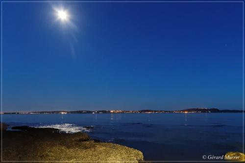 a moonrise over a large body of water at night at Stella Maris in Hyères