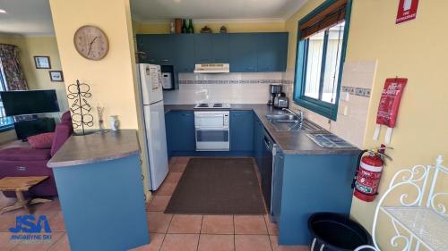 a small kitchen with blue cabinets and a sink at Naturescape in Jindabyne