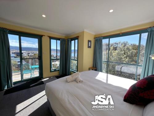 a bedroom with a large bed and large windows at Naturescape in Jindabyne