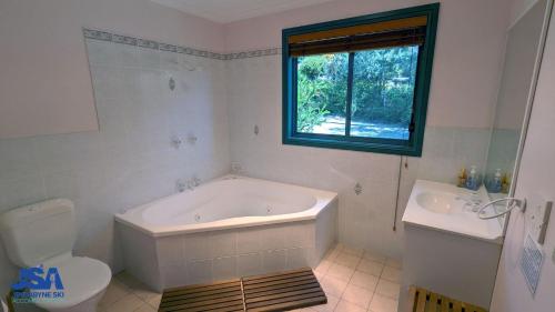 a bathroom with a tub and a toilet and a window at Naturescape in Jindabyne