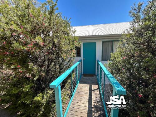 a boardwalk leading to a house with a blue door at Naturescape in Jindabyne