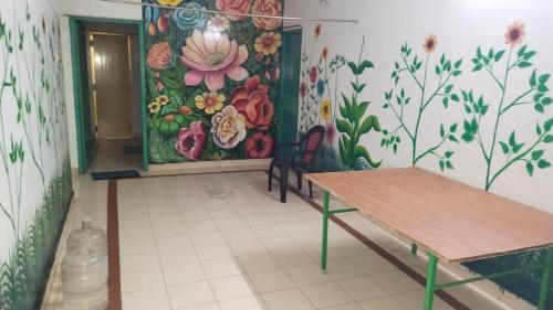 una habitación con una mesa y un mural de flores en la pared en Sunshinehomes en Chennai