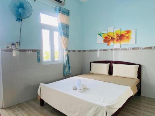 sypialnia z białym łóżkiem i oknem w obiekcie HOA BỈ NGẠN w Ho Chi Minh