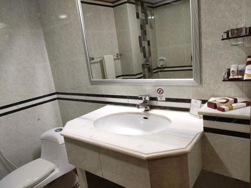 a bathroom with a sink and a toilet and a mirror at Hotel One Karachi in Karachi