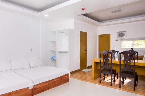 E and c tourist inn في دوماغيتي: غرفة نوم بسرير ومكتب مع كراسي