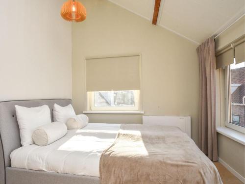 a bedroom with a bed with white sheets and a window at Lovely holiday home with garden in Vrouwenpolder