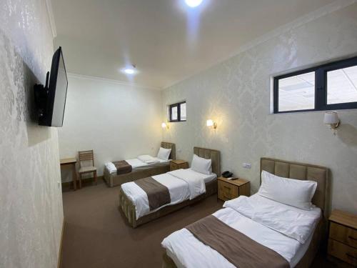 a hotel room with three beds and a television at HOTEL KARVON SHAHRISABZ in Shahrisabz