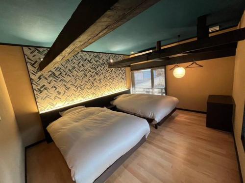 1 dormitorio con 2 camas y pared en 藤左ヱ門の宿, en Sudagai