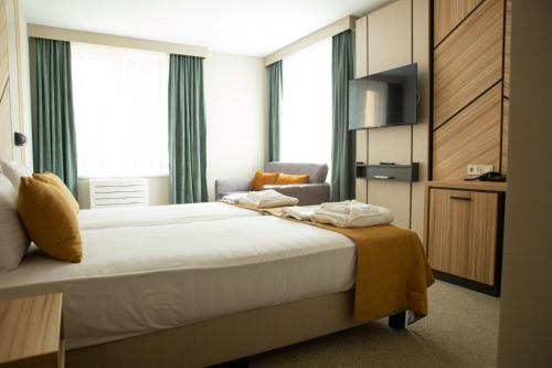 a hotel room with a bed and a chair at Hotel Forum City in Pazardzhik