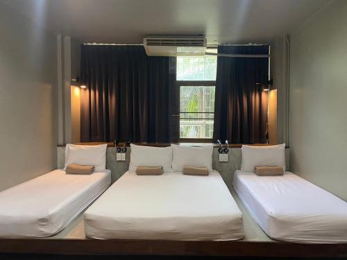 two twin beds in a room with a window at Yaksa Private in Bangkok