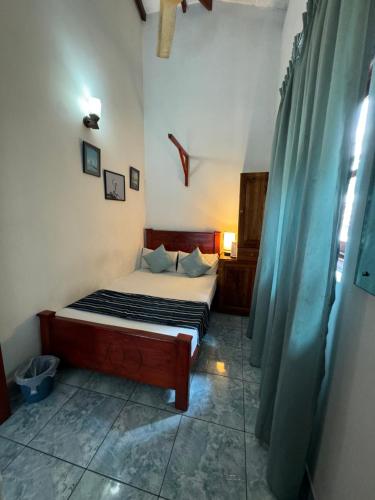 a bedroom with a bed and a blue curtain at Natures Bliss Holidays in Ja-Ela