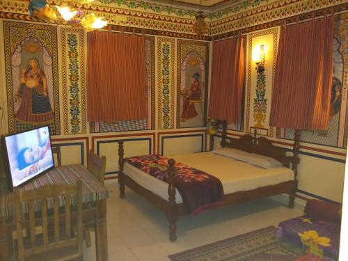a bedroom with a bed and a tv in it at Hotel Shekhawati Haveli in Mandāwa