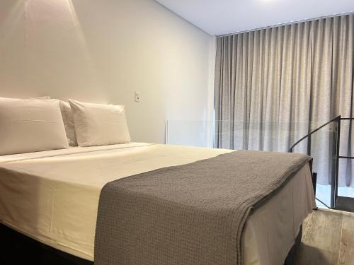 1 dormitorio con 1 cama grande y ventana en Pinheiros Duplex no pool, en São Paulo
