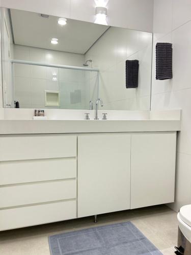 a white bathroom with a sink and a mirror at Pinheiros Duplex no pool in Sao Paulo