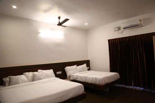 a hotel room with two beds and a ceiling fan at GREEN MOUNT RESORTS in Malaiyāndipattanam