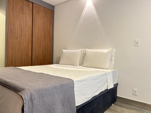 1 dormitorio con 1 cama con sábanas y almohadas blancas en Pinheiros Duplex no pool, en São Paulo