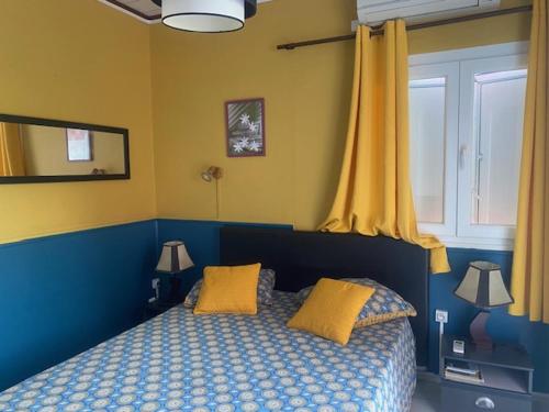 ein Schlafzimmer mit einem blauen Bett mit gelben Wänden und einem Fenster in der Unterkunft Runappart974 in Saint-Louis