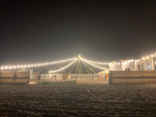 a large tent with lights in a field at night at Dolphin Campground in Barka