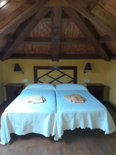 a bedroom with two beds with white sheets at CASA OSO 1 in Pola de Somiedo