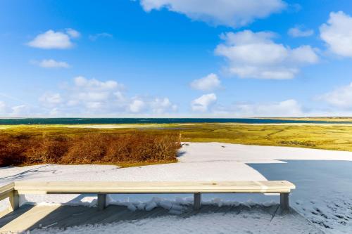 a bench sitting on the beach near the water at Gramse Cape House in Barnstable