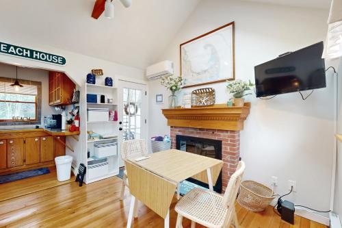 a living room with a table and a fireplace at Cozy Escape on the Cape in Eastham
