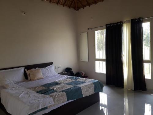 a bedroom with a bed and two windows at ATHARV GUEST HOUSE in Hampi