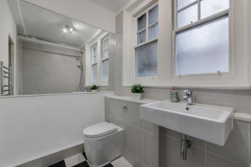 a bathroom with a sink and a toilet and a window at Spacious 1 Bed Apartment- Close to Kings Cross Station in London