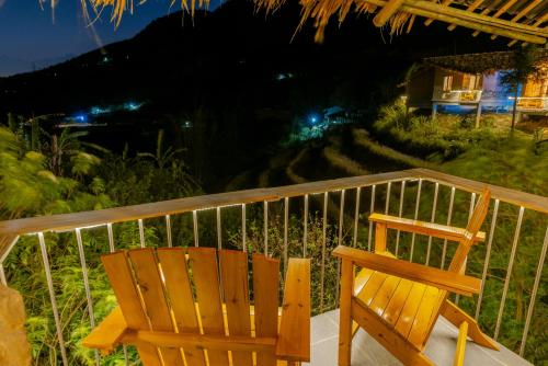 a wooden chair sitting on a porch at night at Sapaxa Spring Garden Ecolodge in Sa Pa