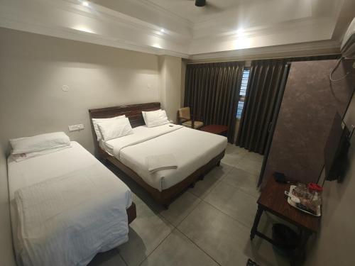 a hotel room with two beds and a television at Hotel Pulikeshi - Since 1987 in Bangalore