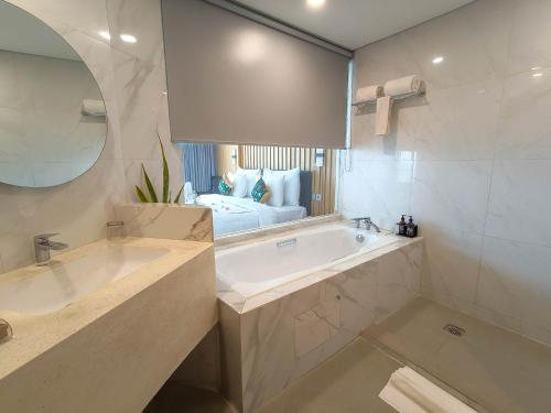 a bathroom with two sinks and a tub with a bed at Raja Hotel Kuta Mandalika Resort & Convention in Kuta Lombok